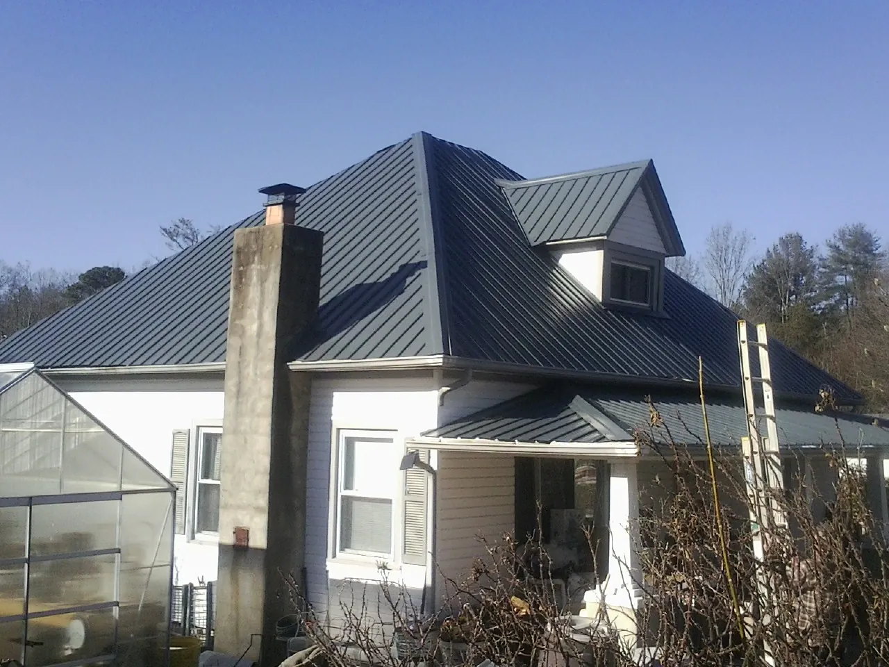 Dark blue standing seam metal roof on a white farmhouse with dormer — Slate & Tile Roof Repair by Roofing Brothers in Haubstadt