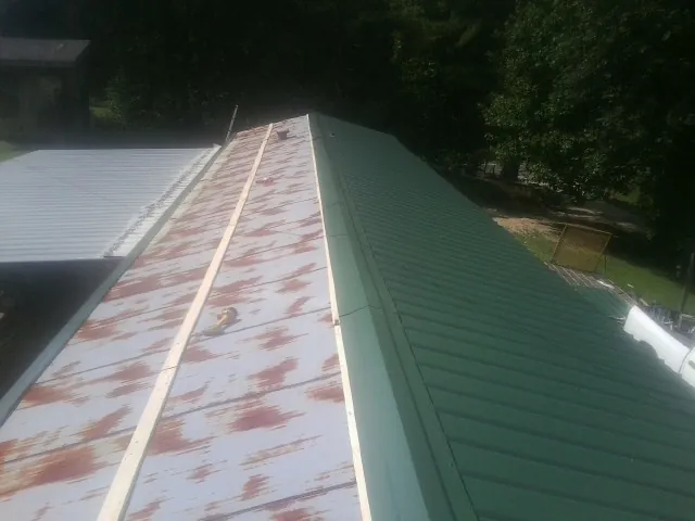 Old rusted panels beside newly installed green metal roofing — Wind Damage Roof Repair by Roofing Brothers in Haubstadt