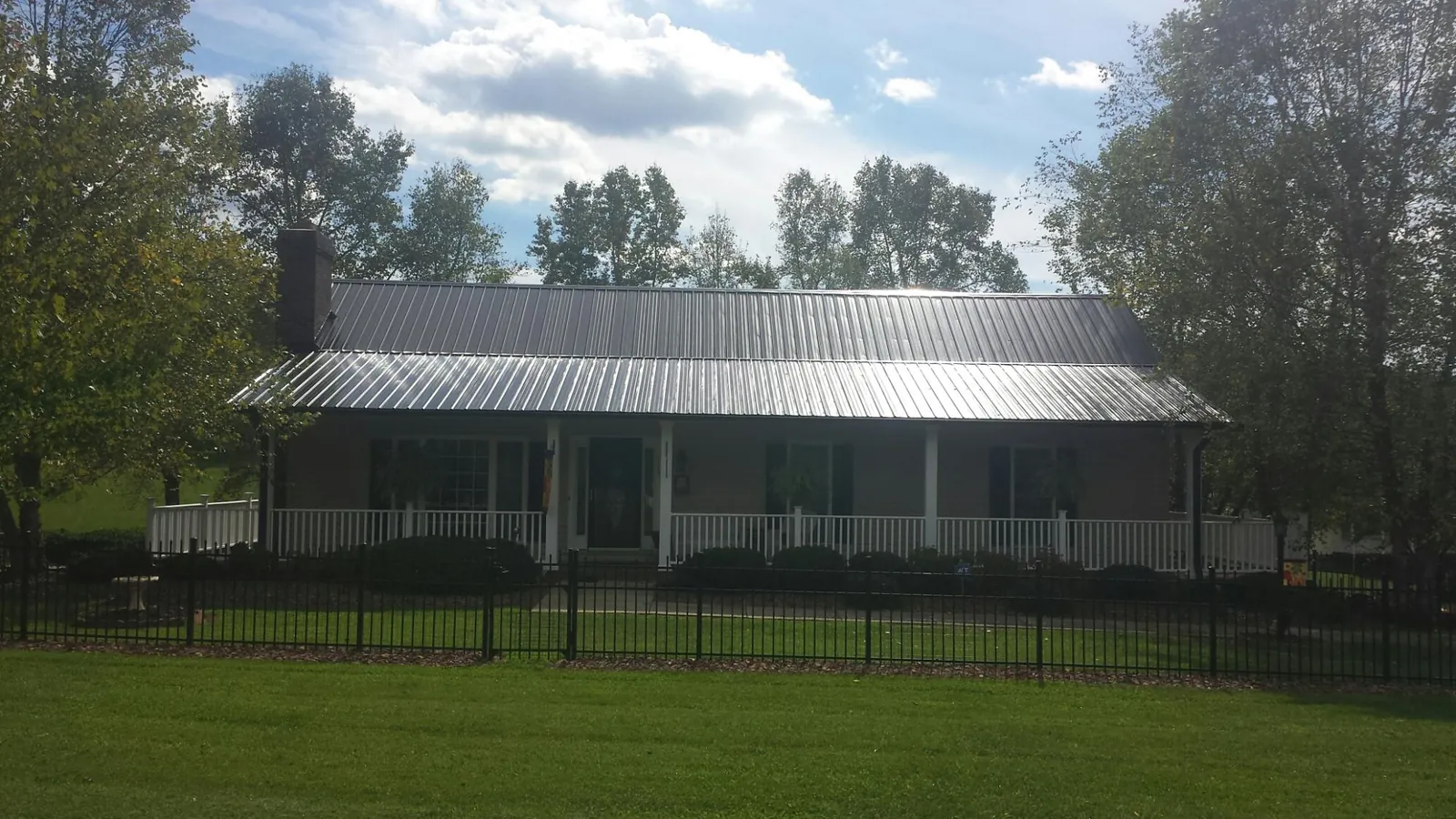 Gray metal roof on a brick ranch with a full width front porch — Gutter Guard Installation work by our crew in Haubstadt