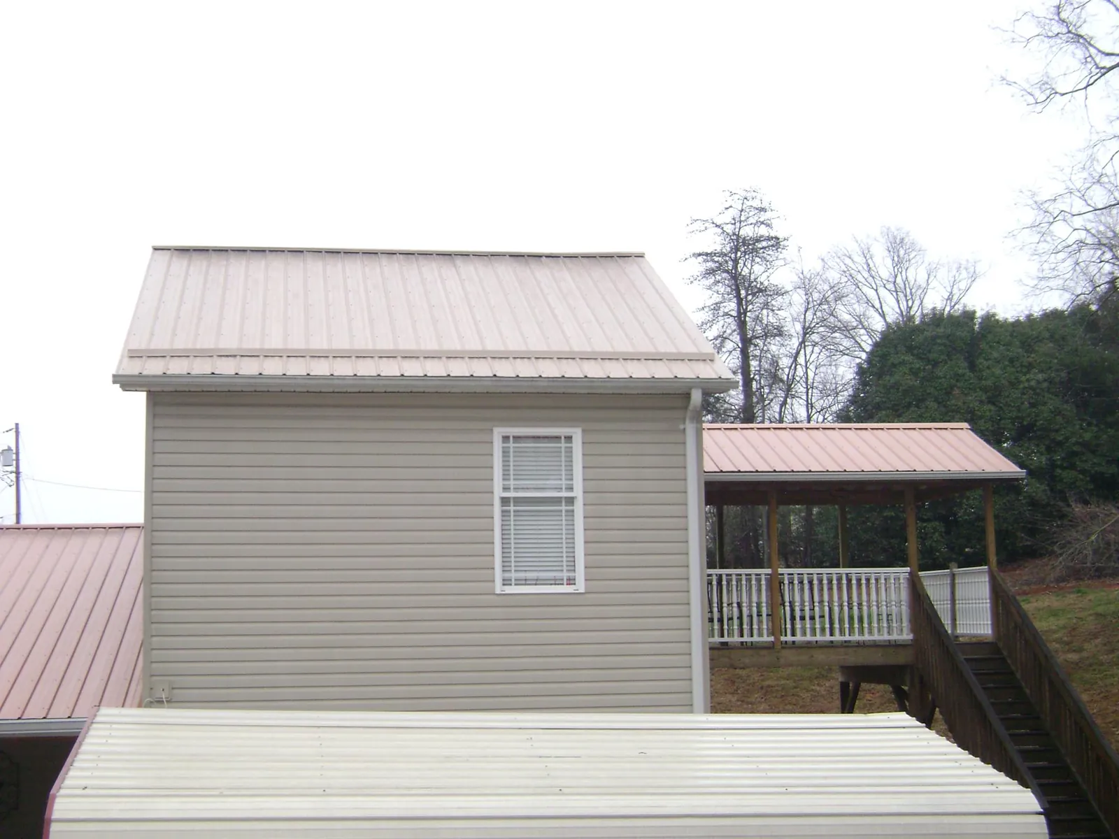 Tan metal roofs on a two story addition and attached porch, from a Roof Replacement job in Haubstadt
