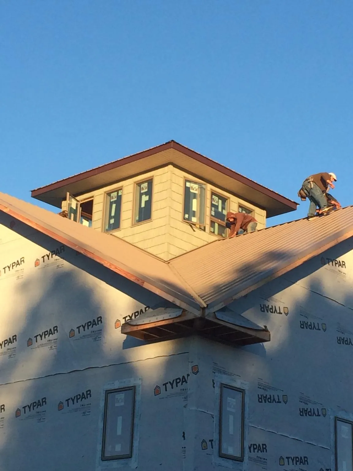Roofers working around a rooftop cupola on a new metal roof at sunset — Roof Waterproofing in Haubstadt by Roofing Brothers